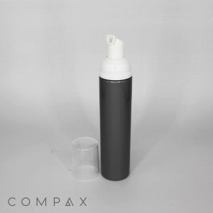 A sleek, dark gray cylindrical 100mL PET bottle with a foamer and an accompanying clear plastic cap beside it. The bottle is labeled "COMPAX" in small, unobtrusive text near the bottom of the image.