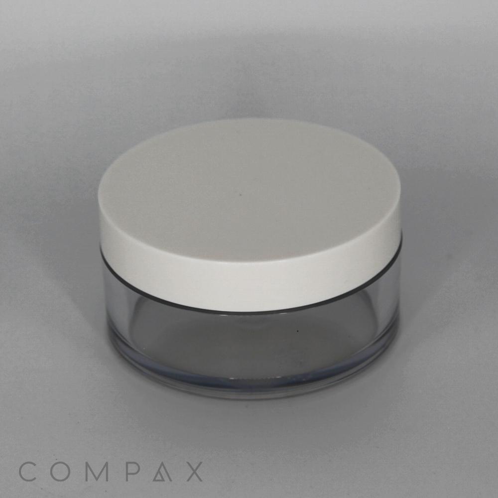 A round, transparent 50mL PET jar with a white short cap is central in the image. The container appears to be designed for holding creams or cosmetics. The word "COMPAX" is subtly printed in the lower left corner of the image. The background is plain and grey.