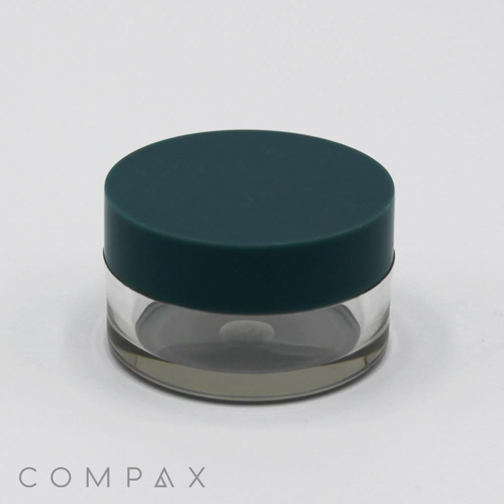 A small, translucent round container with a dark green lid is centered against a plain white background. The 10mL PET Jar appears empty. The brand name "COMPAX" is displayed in light gray text at the bottom left corner of the image.