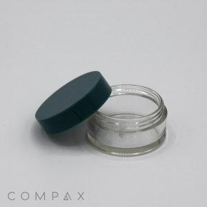 A 10mL PET Jar, clear with a dark green lid partially open, rests on a white surface. The word "COMPAX" is printed in gray text at the bottom left corner.