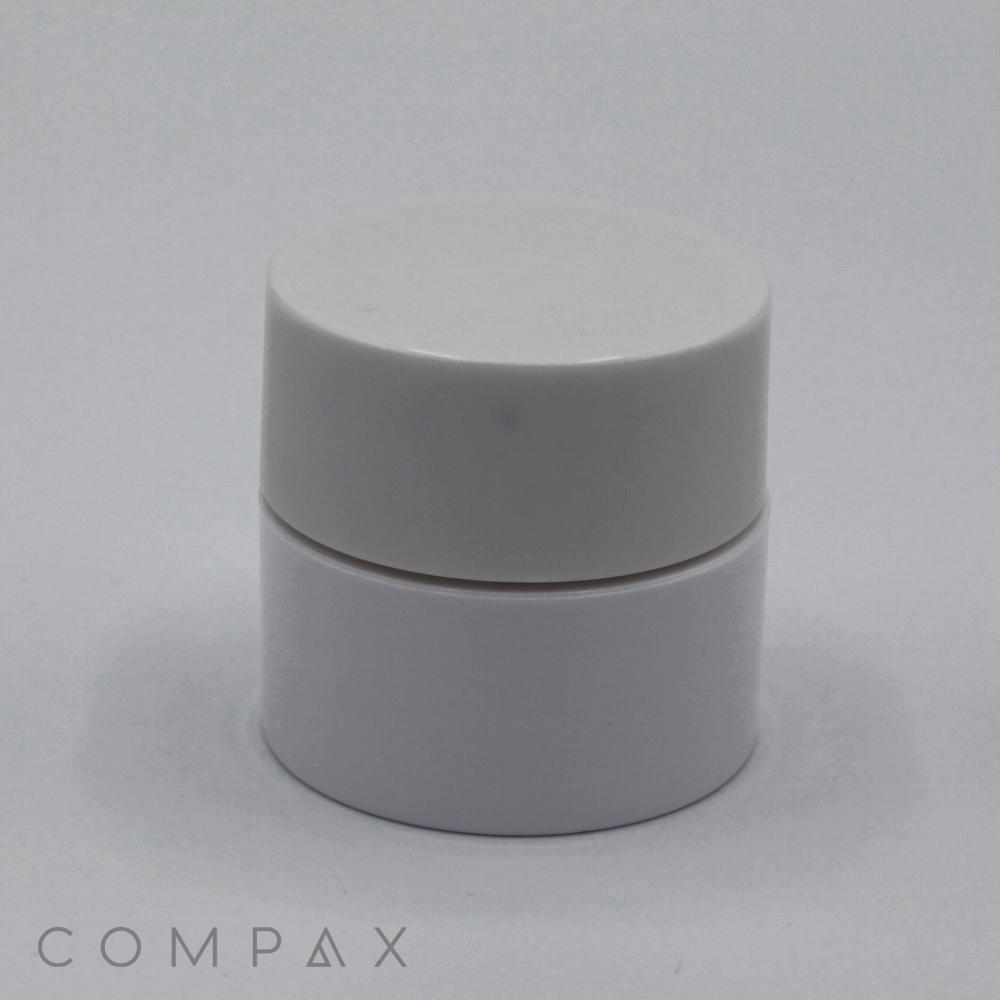 A cylindrical white PET Jar with a smooth surface. The jar appears to have a secure, snug-fitting lid, suggesting it is used for creams or other skincare products. The background is a plain, light gray color. The word "COMPAX" is printed on the bottom.