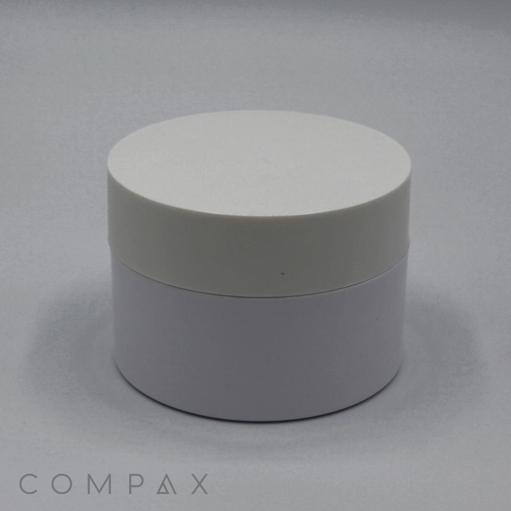 A round, white 100mL PET jar featuring a smooth surface and a tall, flat cap. The sleek container, seemingly made of plastic, sits on a plain light grey background. The word "COMPAX" is subtly displayed in grey text at the bottom left corner of the image.