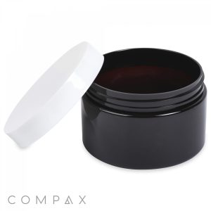 A 300mL PET Jar, black and cylindrical with a white lid, partially open to reveal its empty interior. The backdrop is white, and "COMPAX" is inscribed in light gray at the bottom left corner.