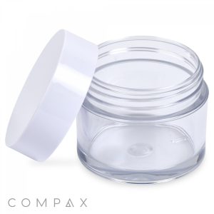 A 60mL PET Jar with a clear plastic body and a white lid angled open, placed beside it. The cylindrical, transparent jar displays no contents inside, and the brand name "COMPAX" is visible in the bottom left corner.