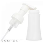 A 100 mL PET Foamer Bottle is shown against a plain white background. The white plastic pump dispenser is slightly angled, with the dispensing nozzle pointing downwards towards the white cylindrical bottle. The brand name "COMPAX" is displayed in light gray text at the bottom-left corner.
