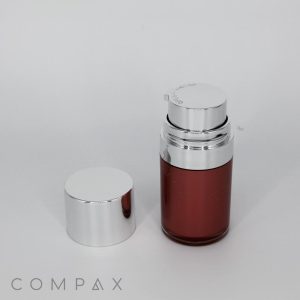 A sleek Round Airless Bottle with a shiny silver cap next to it. The bottle is partially filled with a reddish-brown liquid and features a silver dispensing pump on top. The background is plain white, and the word "COMPAX" is visible at the bottom left in gray text.