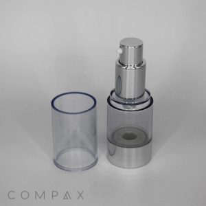 A Round Acrylic Airless Bottle with a silver and clear plastic design, featuring a cylindrical cap removed and placed to the side, stands on a plain white background. The brand name "COMPAX" is displayed in small, gray text at the bottom left corner.