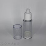A Round Acrylic Airless Bottle, featuring a clear cylindrical design with a white pump dispenser and a transparent cap placed beside it. The bottle appears empty, with the word "COMPAX" visible at the bottom left corner of the image on a light grey background.