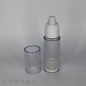 A Round Acrylic Airless Bottle, featuring a clear cylindrical design with a white pump dispenser and a transparent cap placed beside it. The bottle appears empty, with the word "COMPAX" visible at the bottom left corner of the image on a light grey background.