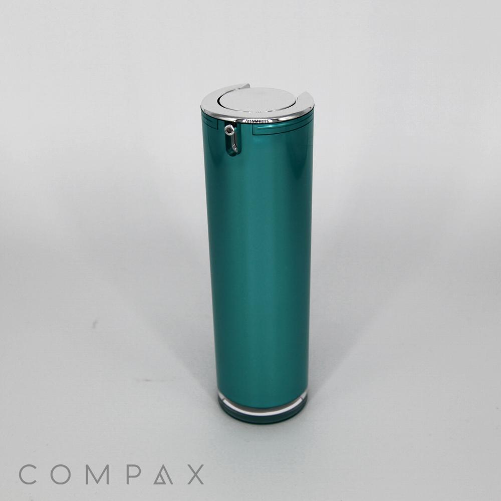 A sleek, cylindrical teal Round Airless Bottle with a silver lid stands upright against a plain white background. The bottle has a minimalistic design with the brand name "COMPAX" in small text at the bottom left corner of the image.