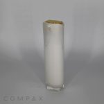 A tall, oblong airless bottle with a white substance inside. The bottle features a gold-colored cap on top. The image has the word “COMPAX” written at the bottom left corner.