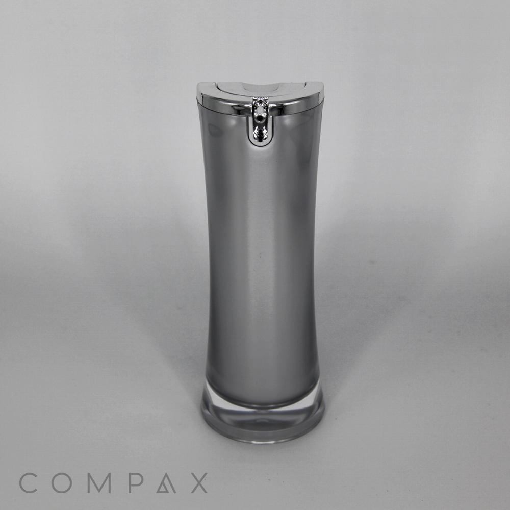 A sleek, grey Hourglass Airless Bottle with a silver cap is standing upright against a plain background. The brand name "COMPAX" is printed in the lower left corner. The design is minimalist and modern.