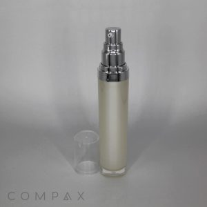 A frosted Round Airless Bottle with a silver cap and nozzle, containing a cream-colored product. The clear plastic lid is removed and placed beside the bottle against a neutral gray background. The word "COMPAX" is visible at the bottom left of the image.