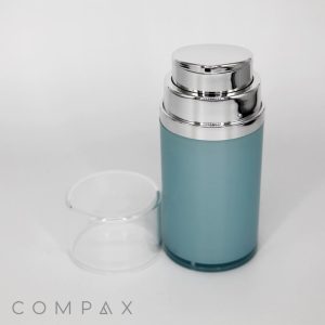 A cylindrical, light blue Squatted Round Airless Bottle with a chrome pump dispenser and a transparent plastic cap removed and placed beside it. The brand name "Compaq" is visible at the bottom left corner of the image.