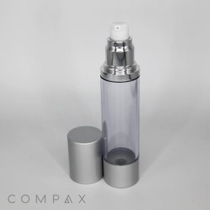 A clear, sleek Round Airless Bottle with a silver cap partially set aside reveals a silver and white pump dispenser on top. The word "COMPAX" is printed at the bottom left corner of the image.