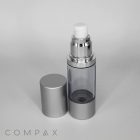 A sleek, transparent Round Airless Bottle with a silver cap placed beside it. The bottle features a modern, minimalist design and the brand name "COMPAX" is visible in the lower-left corner against a plain white background.