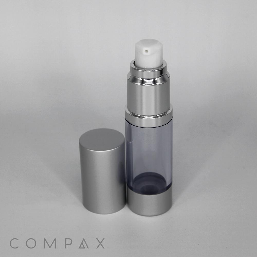 A sleek, silver Round Airless Bottle with its cap placed beside it. The bottle is partially transparent, revealing the inner chamber. The brand name, "COMPAX," is subtly displayed at the bottom left of the image.