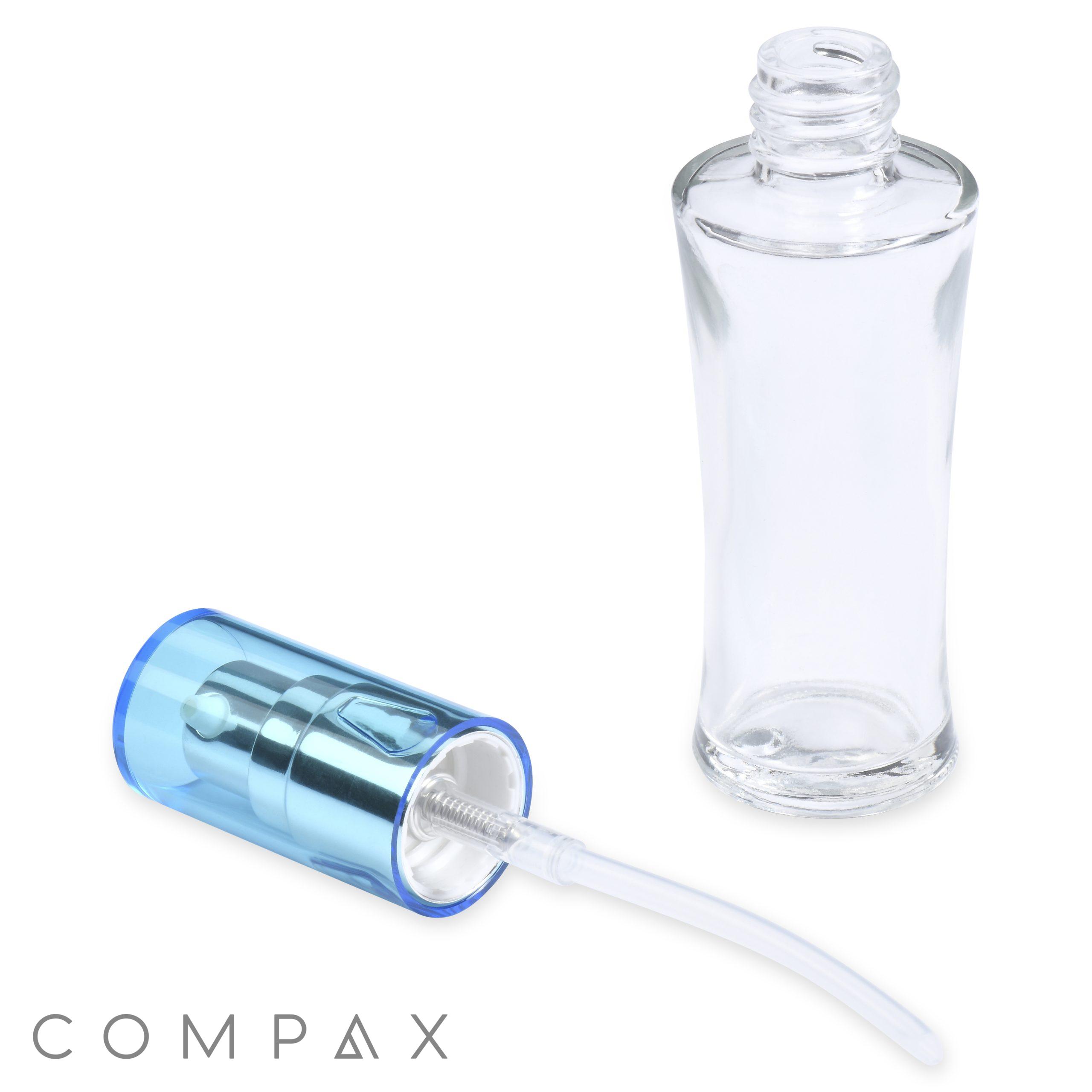 A clear, empty 30mL glass fluted bottle with a detachable metallic blue spray nozzle lies on its side, displaying the internal straw mechanism. The compax brand name is displayed in lowercase at the bottom of the image.