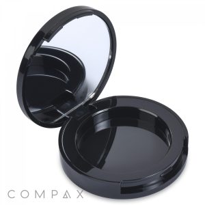 A Round Platform Single Pan Eyeshadow Compact, black and circular with a mirror inside the lid, is open to show an empty compartment. The word "COMPAX" appears in the bottom left corner of the image.