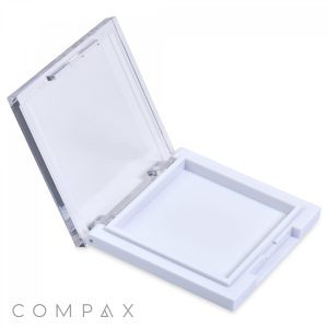 The Square Single Pan Compact features an open square design with a transparent lid and white base. Inside, it's empty and ready to hold products like powder or makeup. The word "COMPAX" is printed in gray at the bottom left corner.