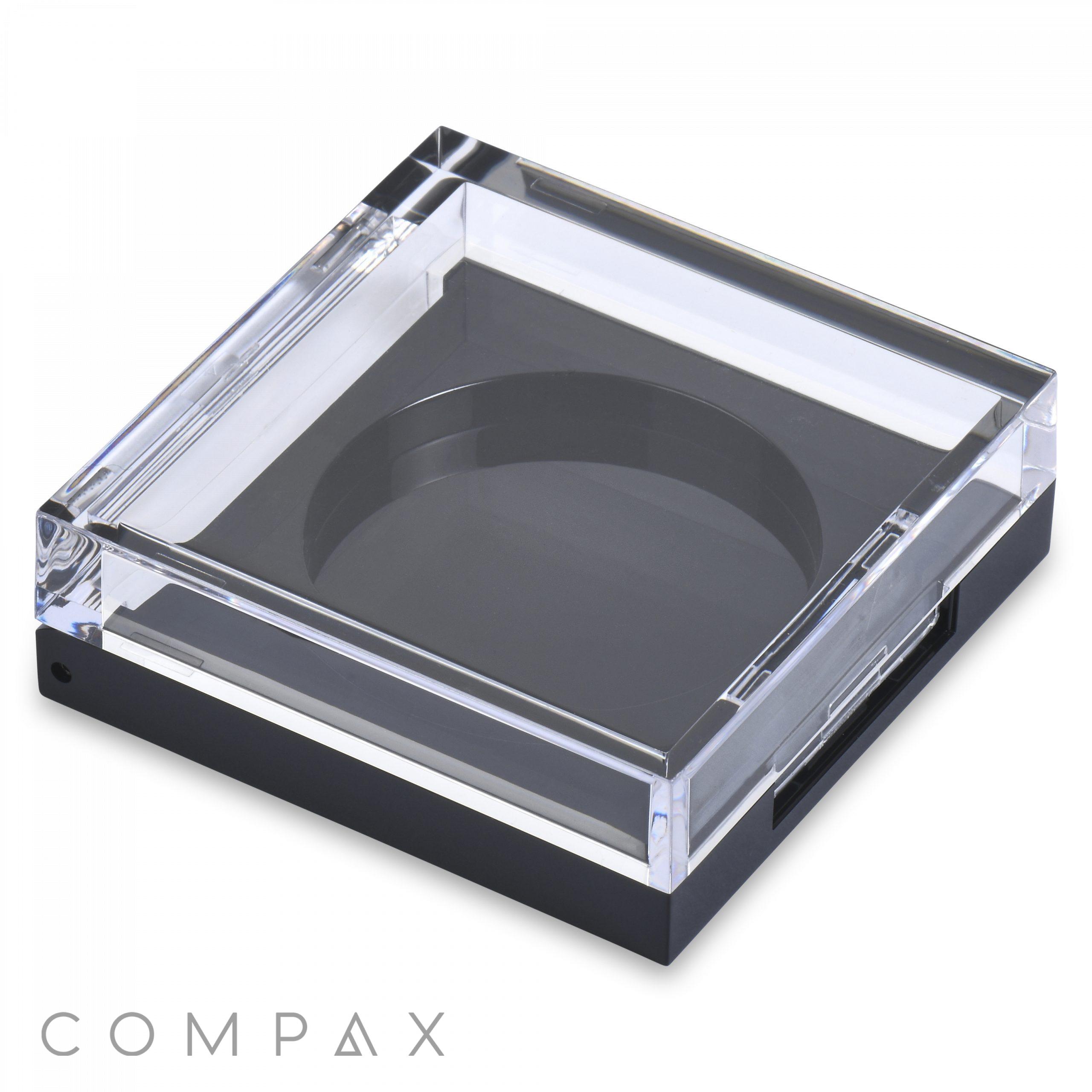 A transparent, square plastic packaging with a black base. The top is clear and allows visibility of its contents, and Square Single Pan Eyeshadow Compact is printed in small, gray text at the bottom-left corner. The overall design is sleek and modern.