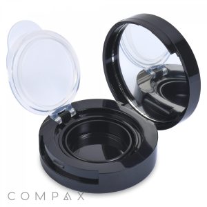 An open Airtight Eyeshadow Compact in black is displayed with its clear lid. The case includes a mirror on the inner side of the lid and a round, empty compartment designed to hold makeup or powder. The brand name "COMPAX" is visible in the bottom left corner.
