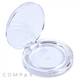A clear, round, open compact case with a hinged lid and the brand name "COMPAX" written on the bottom left corner. This Round Single Pan Eyeshadow Compact is empty, showcasing its transparent design.