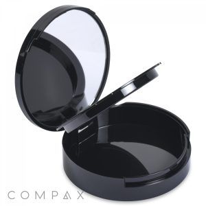 The Round Single Pan Compact with Brush Well is a black makeup compact that features a lid which opens to unveil a mirror on the inside. The lower-left corner displays the word "COMPAX." Inside, there is an empty circular compartment.