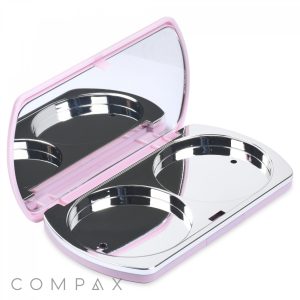 A small, open compact case with a pink exterior and a mirror inside the lid. The interior features two circular metal compartments designed to hold makeup, such as eyeshadow or blush. The brand name "COMPAX" is visible in the bottom left corner of the image. This item is known as the Bullet 2 Round Pan Powder Compact.