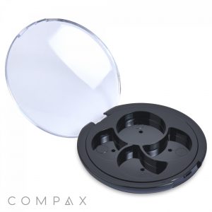A round, black Round 4 Pan Pinwheel Eye Shadow Compact with an open, clear plastic lid. The interior features three compartments to securely hold individual items. The word "COMPAX" can be seen in the bottom left corner of the image.