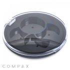 The Round 4 Pan Pinwheel Eye Shadow Compact is a transparent, circular container divided into four compartments with a snap-on lid. The base of this compact is black, and the clear lid showcases the sections inside. The word "COMPAX" can be seen in the bottom left corner on the outside of the container.