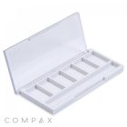 An open, square white plastic container labeled "Square Six Pan Eyeshadow Compact," featuring a transparent lid with six compartments arranged in two rows. The word "COMPAX" is visible in the bottom left corner.