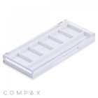 A Square Six Pan Eyeshadow Compact, featuring a white rectangular box with a clear lid and six compartments inside. The box is positioned diagonally, showcasing the depth of the compartments. The word "COMPAX" is visible in grey letters at the bottom left corner of the image.