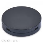 A sleek, round, black "Single Pan Compact" case with a minimalist design. The case is closed and boasts a smooth, glossy finish. "COMPAX" is inscribed in light gray text at the bottom left corner of the image.