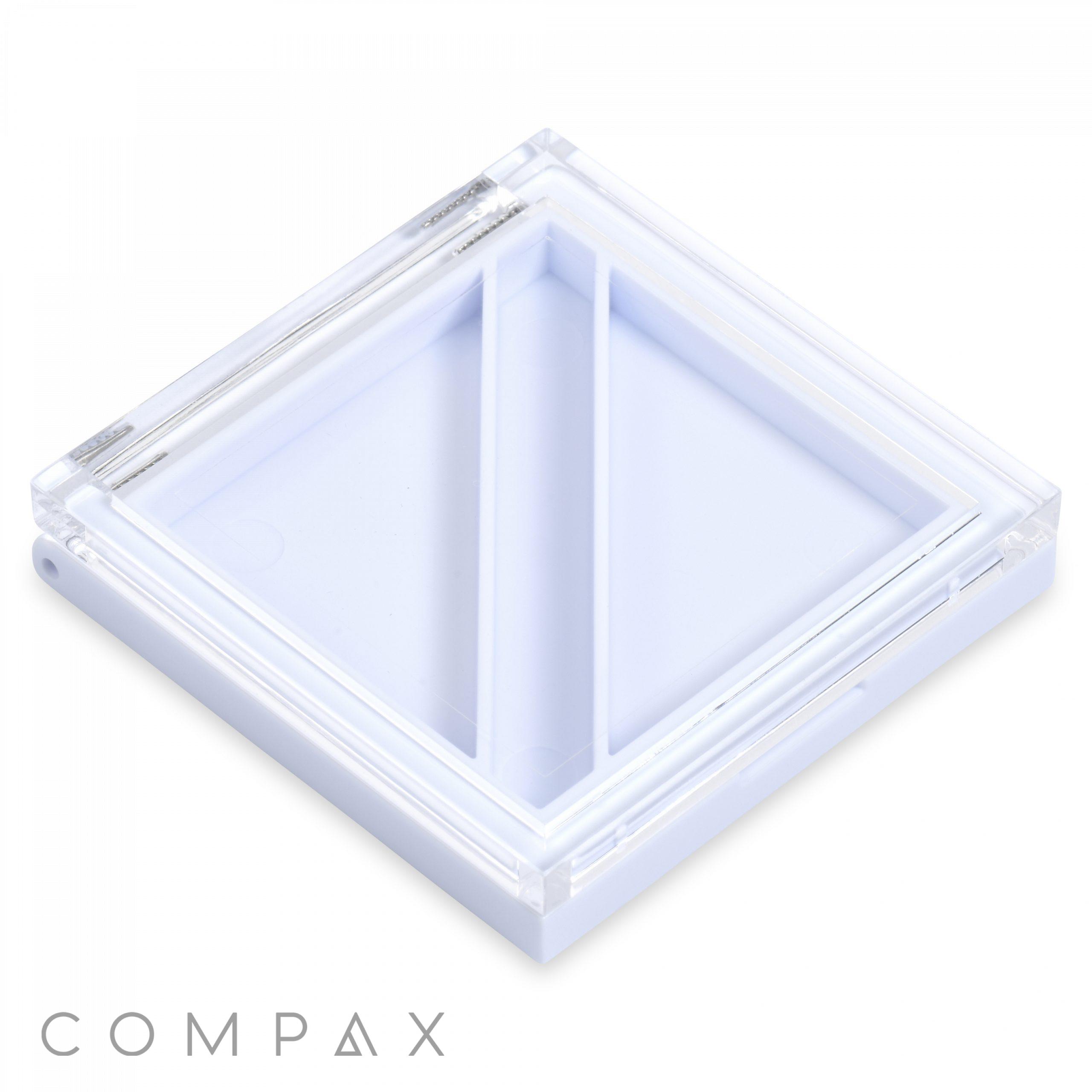 A transparent square compact with a divided interior featuring two triangular compartments. The compact, shown from a slightly angled top view, has a clear lid and a white base. "Square 2 Pan Compact with Brush Well" is marked at the bottom left corner.