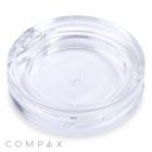 A Round Single Pan Eyeshadow Compact is displayed against a white background. The clear plastic compact case, featuring a transparent lid, appears empty. The brand name "COMPAX" is visible at the bottom left corner of the image.
