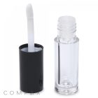 A Mini Lip Gloss container with a black cap is displayed. The cap, featuring a white applicator wand, stands next to the open container. Made from transparent material, the empty container prominently displays the brand name "COMPAX" at the bottom.