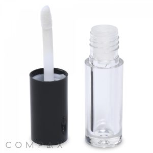 A Mini Lip Gloss container with a black cap is displayed. The cap, featuring a white applicator wand, stands next to the open container. Made from transparent material, the empty container prominently displays the brand name "COMPAX" at the bottom.