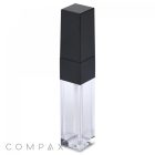A sleek, transparent Square Lip Gloss tube featuring a black, angular cap. The tube appears nearly empty, highlighting its minimalistic and modern design. The "COMPAX" logo is subtly branded in the bottom left corner.