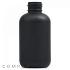 A 4oz Boston Round Bottle crafted from matte black plastic, featuring a cylindrical shape and a wide, threaded neck. The bottle is plain without any labels or markings, with the branding "Compax" visible in the bottom left corner of the image.
