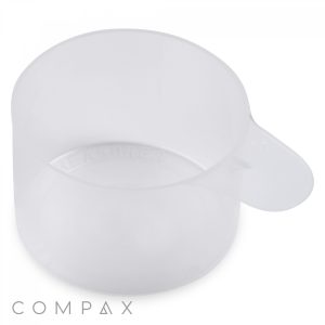 A clear plastic 60cc scoop with a handle, viewed from the top and slightly to the side. The measuring marks are faintly visible on the inside surface. The image has the word "COMPAX" written in light gray at the bottom left corner.