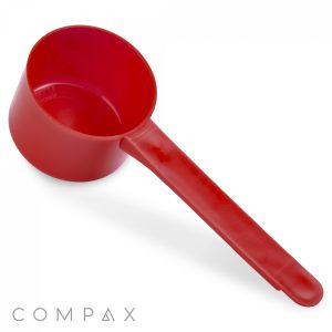 A 47cc red plastic measuring scoop with a long handle, placed on a plain white background. The brand name "COMPAX" is visible at the bottom left corner of the image.