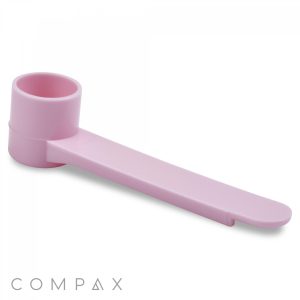 A pink, plastic 2.5cc Scoop features a cylindrical cup at one end and a long, flat handle at the other. The cup is designed to fit over specific containers or objects. The brand name "COMPAX" appears at the bottom left corner of the image.
