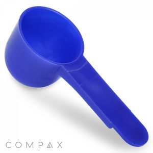 A 1cc Scoop made of blue plastic features a short, rectangular handle. Its rounded bowl is designed for measuring powders or granules. The word "COMPAX" appears in gray at the bottom left corner, all set against a white background.