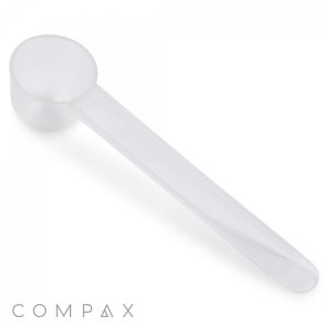 A translucent plastic 1cc Scoop with a long handle is centered against a white background. The handle is elongated, and the scoop is round and open. The bottom left corner features the brand name "COMPAX" in gray, uppercase letters.