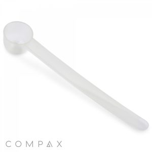 A translucent white "1cc Scoop" made of plastic, featuring a long handle and a small rounded cup at the end. The "COMPAX" logo is visible in the bottom left corner of the image.