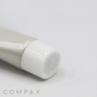 A 16mm Screw Top tube with a white cap is partially visible against a light grey background. The embossed text "COMPAX" appears in the bottom-left corner of the image. The tube is angled slightly to the left, and the image focuses on the cap end.