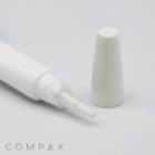 A close-up image of a white tube labeled "16mm Brush Applicator" with a clear, pointed applicator tip and a removed white cap. The brand name "COMPAX" is visible in light gray letters at the bottom left corner of the image. The background is a plain, light surface.