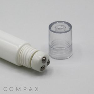 A white cylindrical 19mm Roller skincare tool features three metallic roller balls at one end and a clear plastic cap beside it. The word "COMPAX" is displayed in gray text at the bottom left corner of the image.