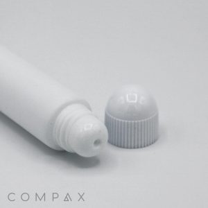 A 19mm Lip Applicator, featuring a white cylindrical tube with a detached cap placed next to its open end. The dispensing end has a small hole for applying the product. The word "COMPAX" is printed in gray at the bottom left corner of the image.